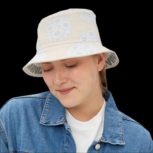Person wearing a beige bucket hat with floral patterns and a denim jacket on a white background